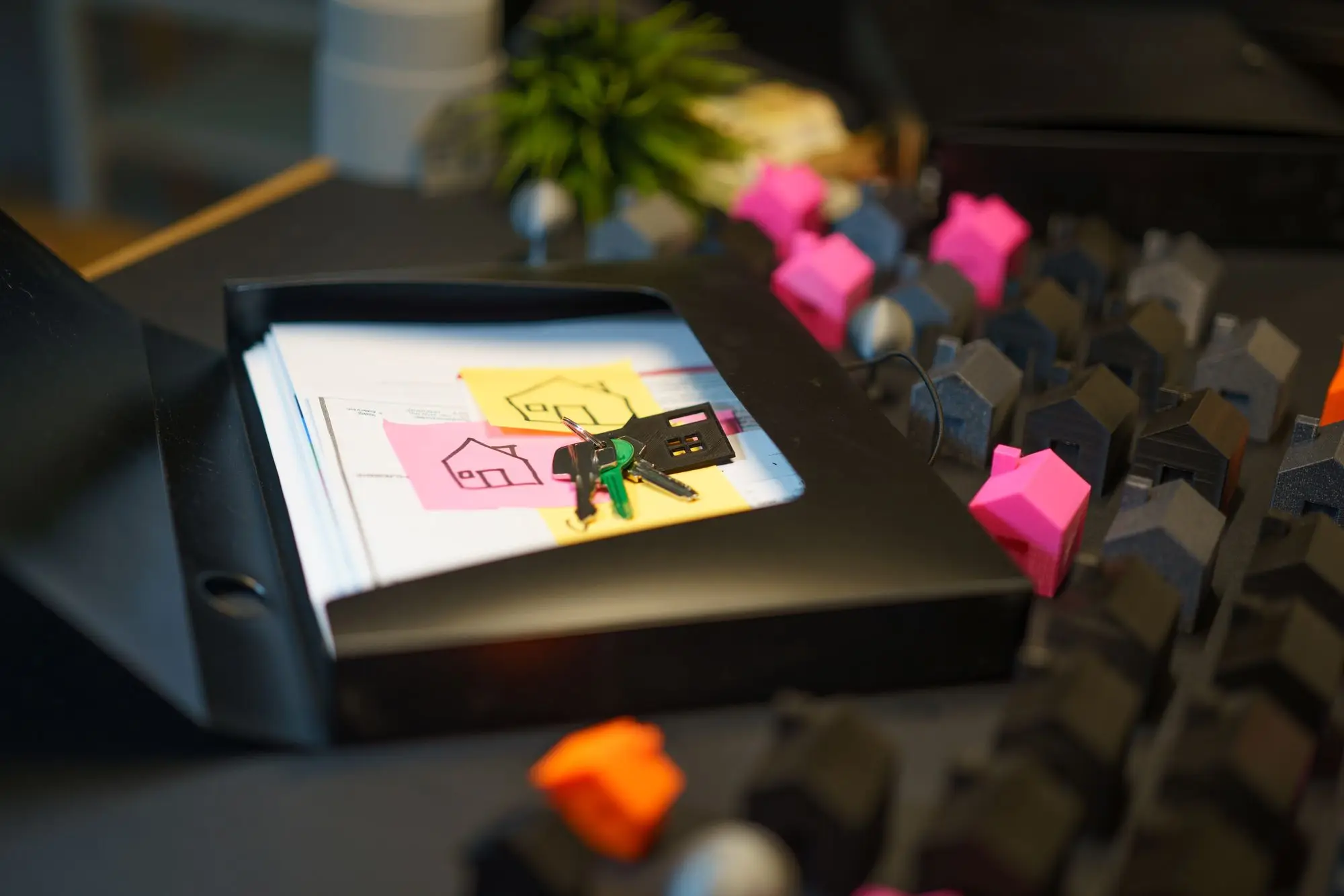 Property keys resting on a folder of sale contract papers marked with house sketches, beside rows of small model buildings